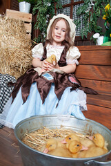 a girl in a Disney Cinderella costume holds a duckling next to a basin of iron with animals for...