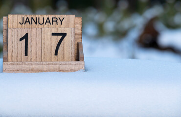 Wooden calendar of January 17 date standing in the snow in nature.