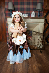 A child in a Cinderella carnological costume holds wood and wood near the fireplace in a cassette...