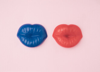 Blue and red lips next to each other on a light pink background. The minimal concept of a couple in love