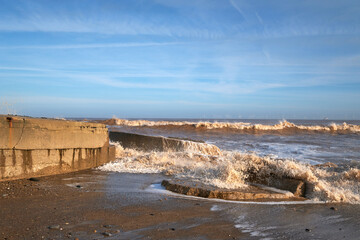 Waves crashing over concrete blocks on a beach