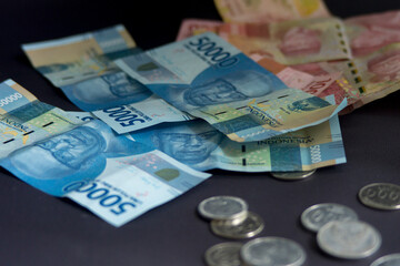 Money scattered on a black background. Indonesian Rupiah Good for economy concept. Coin Illustration. fiat money.