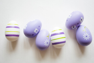 painted easter purple eggs with ornament and decor on white light pastel background. copy space