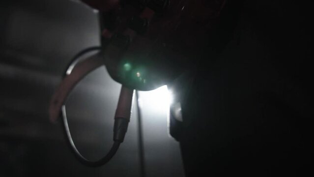 A close-up of a slow-mo musician plugging his guitar into an amplifier before performing. Popular music using electric guitar in concert. Spotlight beams shine on the stage