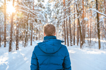 A young blond man in a spruce snow forest on a sunny day in winter. Beautiful nature, winter hiking
