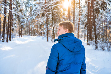 Fototapeta na wymiar A young blond man in a spruce snow forest on a sunny day in winter. Beautiful nature, winter hiking