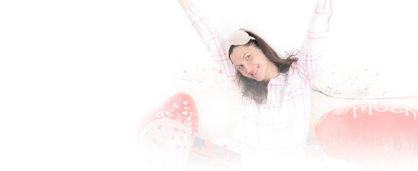 A beautiful woman in pink pajamas with a heart-shaped balloon lies on bed at home. Woman on Valentine's Day, birthday or anniversary. Love symbol. Banner with copy space