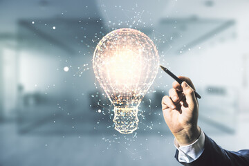 Man hand with pen working with abstract virtual light bulb hologram on blurred office background,...