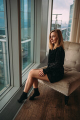 A girl at the window with a beautiful view of tall glass buildings