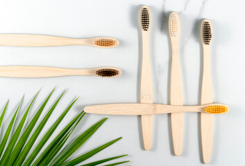 bamboo toothbrushes, palm leaf decor on gray concrete background.