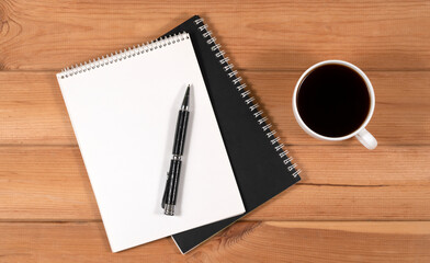 coffee cup, blank notepad and pen on wooden background, top view