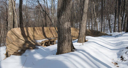 Elevated turn on a mountain biking trail.  Wooden cycling berm. Winter snow.