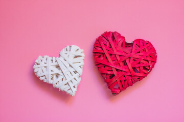white and red braided heart close-up on a pink background. concept of love, valentine's day and romance.