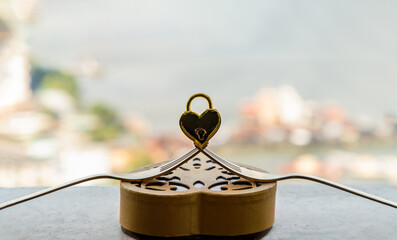 Golden heart shaped love padlock over two intertwined gold forks on Gold heart-shaped box....