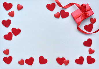 Valentines Day background. Red gift box with ribbon and hearts on a pastel blue background. Top view