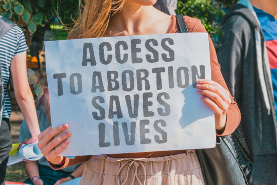 The phrase " Access to abortion saves lives " drawn on a paper in woman hands. Caucasian woman with light hair holds a cardboard with an inscription. Society. Sex. Rescue. Justice. Maternity. Problem