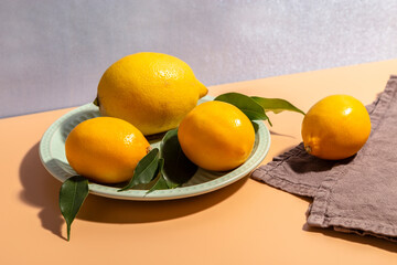 Fresh lemons on a plate on a bright background.
