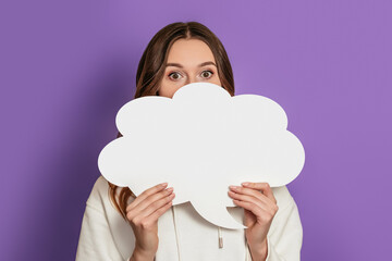 Student girl holding blank speech bubble paper isolated on purple background. White paper cloud for text on veri peri color 2022. Copy space