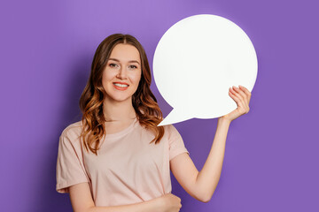 young woman holding blank speech bubble paper isolated on purple background. female student holding a sheet of paper in the shape of a circle dialog