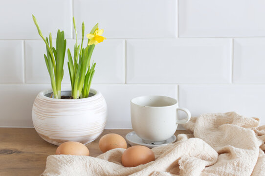 Spring, Easter breakfast still life. A cup of coffee, narcissus, daffodil flowers, hen eggs, and empty picture frame mockups. Linen tablecloth. Farmhouse, Scandinavian interior.