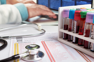 Doctor working with Hematology blood analysis report with rack blood tubes and stethoscope. Blood...