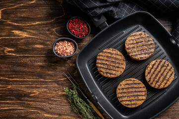 Grilled Vegetarian plant based meat burger patties,  vegan cutlets on grill skillet. Wooden...