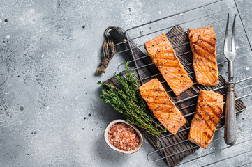 Grilled salmon fillets steaks with salt pepper and herb on grill. Gray background. Top view. Copy...