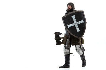 Full-length portrait of brave man, medieval knight, warrior with shield and ax calmly walking...