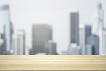 Empty wooden tabletop with beautiful blurry skyscrapers in the afternoon on background, mock up