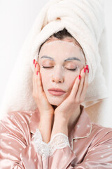 Face care and beauty treatments. Woman with a sheet moisturizing mask on her face isolated on white...