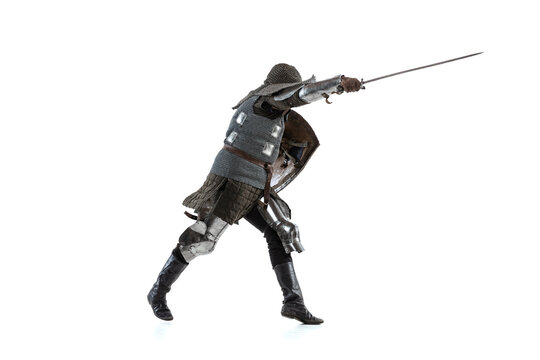 Portrait of brave medieval warrior, knight in special coat of mail attaching with sword isolated over white studio backgrond