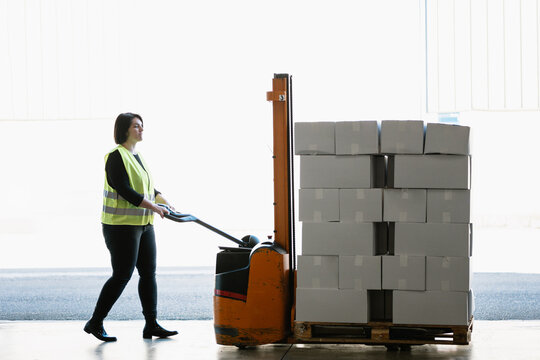Woman pushing stacker with boxes