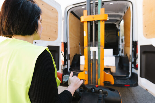 Anonymous woman loading boxes with stacker