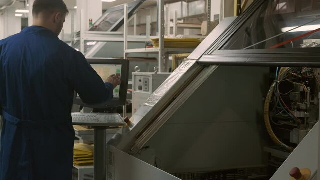 Operator at Modern robotic production works on high-tech equipment. person controls large automated machine enters data into  program. Digital industry of high-precision technologies