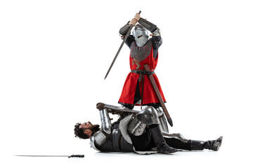 Full-length portrait of two medieval warriors, knights fighting isolated over white studio...