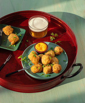 Codfish fritters server on tray with fresh herbs and glass of beer