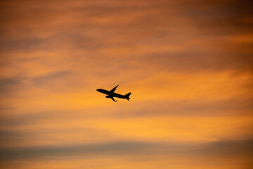 Fototapeta na wymiar Airliner flying over colorful sunset