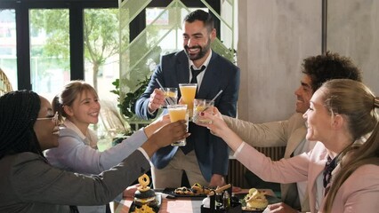 Group of businesspeople in a restaurant toasting at business lunch.