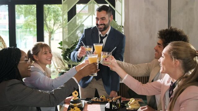 Group of businesspeople in a restaurant toasting at business lunch.