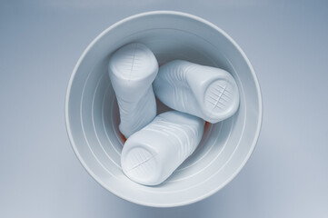White plastic bottles in a trash can on a white background