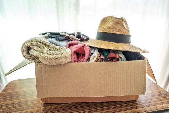 Holding clothing donation box with used clothes and hatl at home to support help for poor people in the world.