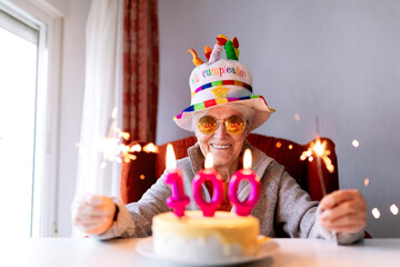 Smiling elderly woman with sparklers celebrating hundredth birthday