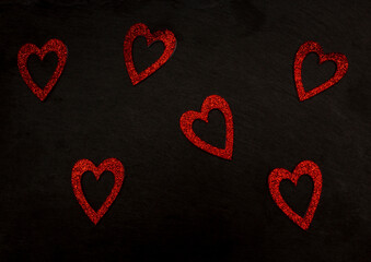 Glossy red hearts on black background. Love valentine concept. Flat lay