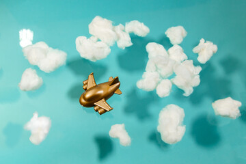 Toy plane flies among white cotton clouds on a pastel blue background.