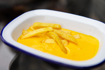 The concept of fast food and fast food. French fries sit in a plate along with cheddar cheese sauce. Top view, close-up.