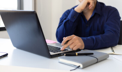 Businessman contemplating while working on laptop in office.