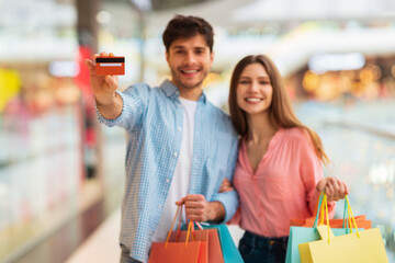 Happy Couple Shopping And Showing Credit Card In Mall Indoors