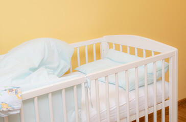 empty baby cot with bedding