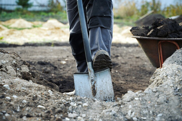 Working with garden tools, shovel and wheelbarrow on the site of a country house. Preparation for construction work.