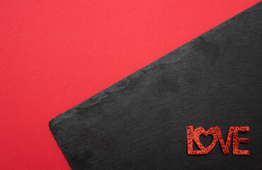 Glossy red letter message LOVE on black stone plate on red background. Love valentine concept. Flat lay